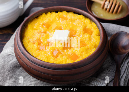 Hirsebrei mit Kürbis in einer Ton-Schüssel auf einem rustikalen hölzernen Hintergrund. Stockfoto