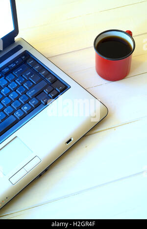 Tasse Kaffee und Laptop auf weißer Holztisch Stockfoto