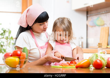 Mutter Kind machen Salat in Küche zu unterrichten. Mutter und Kind Gemüse auf Schneidebrett mit Messer zerkleinern. Kochen Konzept der ha Stockfoto