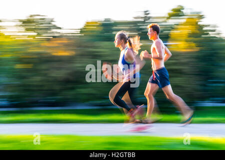 Panning Shot, junge Frau und junger Mann in Sportbekleidung joggen durch den Park, München, Upper Bavaria, Bavaria, Germany Stockfoto