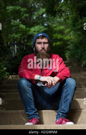 ASkater Mann sitzt auf der Treppe im park Stockfoto