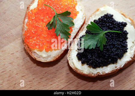 Zwei Sandwiches mit roten und schwarzen Kaviar auf Holzbrett Stockfoto