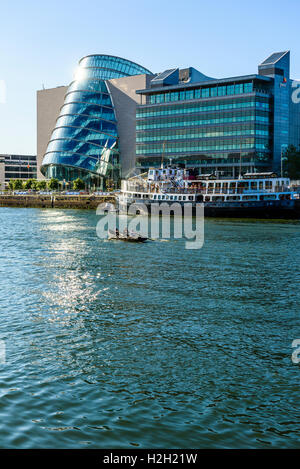 Drachenboot am Fluss Liffey Dublin Irland mit Convention Centre Dublin, Büros von Pwc und MV Cill Airne schwimmendes Restaurant Stockfoto