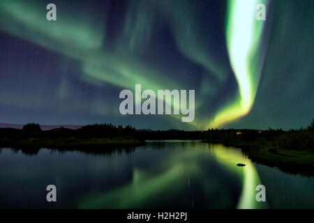 Polarlichter über Eillidavatn in der Nähe von Reykjavik in Island. ruhiges Wasser reflektiert das Nordlicht am Himmel lodernden. Stockfoto