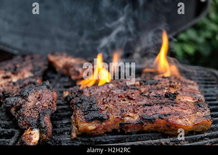 Stück Fleisch auf dem Grill, Flammen präsentieren sich ihnen Stockfoto