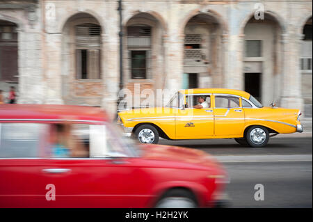 Havanna - 13. Juni 2011: Bunte Vintage American Taxi Autos teilen die Straße in Bewegungsunschärfe an der Uferpromenade Malecon. Stockfoto