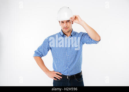Ernster junger Mann Bauingenieur im harten Hut stehen und posiert Stockfoto