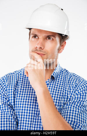 Nachdenklicher junger Mann Bauingenieur im Helm stehen und denken Stockfoto