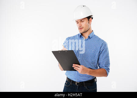 Junger Mann-Generator beim Aufbau Helm schreiben in Zwischenablage konzentriert Stockfoto