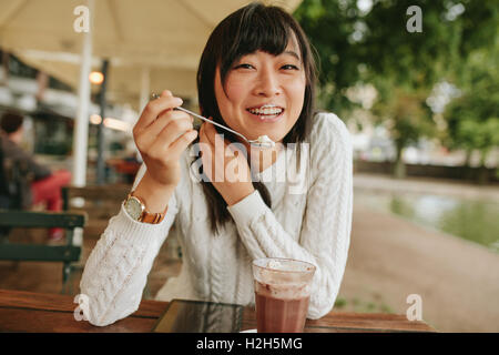 Schuss der glückliche junge Frau in Essen kaltes Dessert Eis Straßencafé. Chinesische Frau Dessert im Café zu genießen.