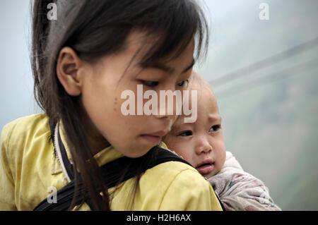 Baby auf dem Rücken ihrer Schwester in der Provinz Ha Giang, Nord-Vietnam Stockfoto