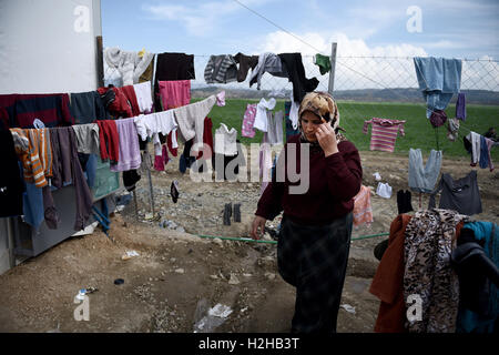 Eine Frau geht neben Erhängten Kleidung vor einem Zelt in einem Flüchtlingslager an der nördlichen griechischen Dorf Idomeni an der griechischen mazedonischen Grenze. Tausende von Flüchtlingen und Migranten saßen monatelang an der griechischen mazedonischen Grenze, im Flüchtlingslager in der Nähe des Dorfes Idomeni, bis die griechische Regierung beschlossen, das Gebiet zu evakuieren. Stockfoto