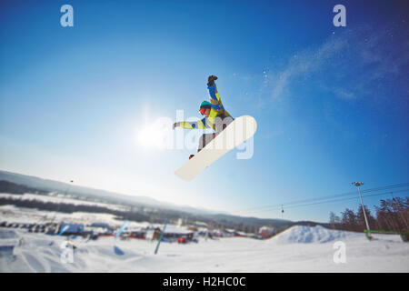 Junge Sportler über Wintersportort auf Skateboard fahren Stockfoto