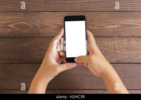 Telefon in der Hand der Frau mit weißen Schirm auf Holztisch, Mock-up neue Telefon Stil Jet schwarz Stockfoto