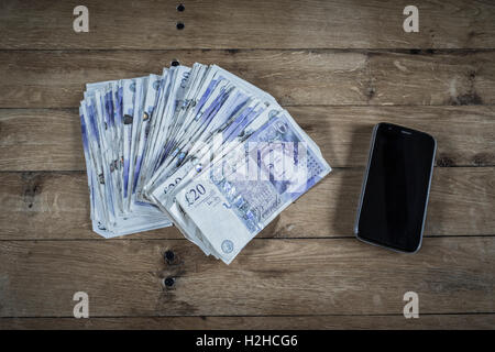 Haufen von zwanzig Pfund-Noten und ein Mobiltelefon. Stockfoto