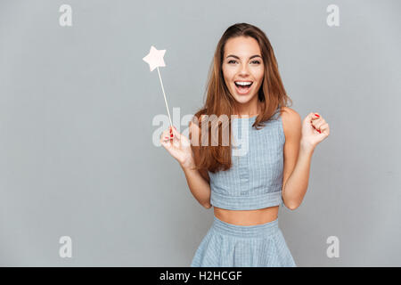 Happy begeistert junge Frau mit Zauberstab auf grauem Hintergrund Stockfoto