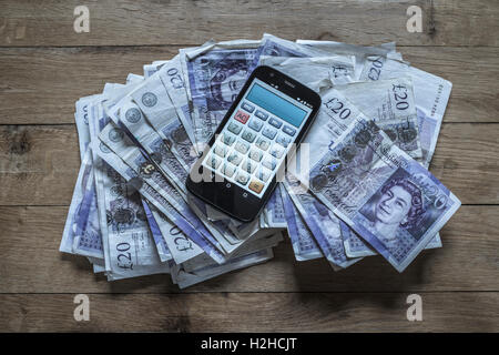 Haufen von zwanzig Pfund-Noten und ein Handy-Rechner. Stockfoto