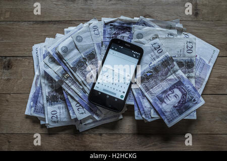 Haufen von zwanzig Pfund-Noten und ein Mobiltelefon. Bestechung-Konzept. Stockfoto