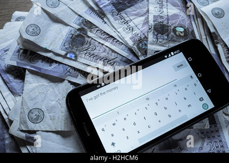 Haufen von zwanzig Pfund-Noten und ein Mobiltelefon. Bestechung-Konzept. Stockfoto