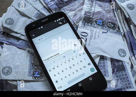 Haufen von zwanzig Pfund-Noten und ein Mobiltelefon. Bestechung-Konzept. Stockfoto