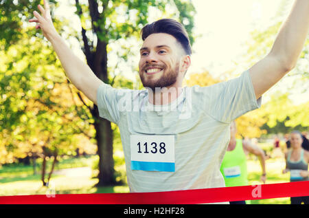 glückliche junge männliche Läufer gewinnen auf Rennen beenden Stockfoto