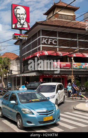 Indonesien, Bali, Kuta, Jalan Pantai Kuta, Bluebird taxi vorbei Kentucky Fried Chicken-Fast-Food-shop Stockfoto