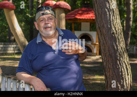 Outdoor Portrait von positiven ukrainischen Bauern stehen hinter Holzzaun Stockfoto