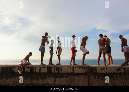 Kinder in ihren Badeanzügen stehen entlang der Ufermauer etwa entlang des Malecón in Zentral-Havanna, Kuba schwimmen zu gehen. Stockfoto