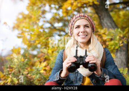 Schöne junge Frau Holding Fernglas, bunten sonnigen Herbst Stockfoto