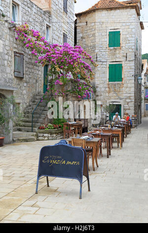 Familie sitzen in einem Restaurant im Freien in einer engen Straße, Stari Grad, Insel Hvar, Kroatien, Dalmatien, dalmatinische Küste Europas. Stockfoto