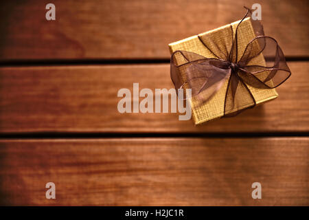 Goldenen Geschenkbox mit braunen Band auf Tabelle Holzlatten. Ansicht von oben Stockfoto