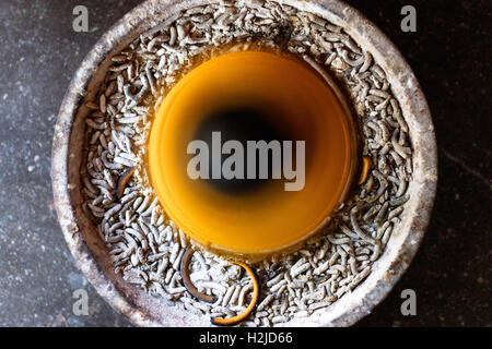 Eine Spirale von Weihrauch über einen Fuß hoch, von oben, Tropfen Asche in das Becken unten gesehen, wie es im Tempel Foyer brennt. Stockfoto