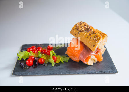 Geräucherter Lachs Vollkorn Sandwich mit Salat aus Kopfsalat, Cherry-Tomaten und Perlen von Olivenöl. Stockfoto