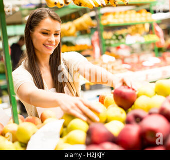 Hübsche junge Frau, die Äpfel auf dem Markt zu kaufen Stockfoto