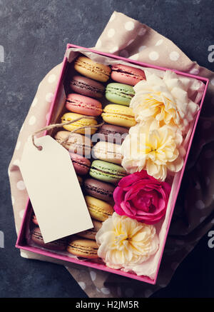 Bunte Makronen und Blumen am Steintisch. Süßen Macarons in Geschenkbox. Ansicht von oben. Getönten Stockfoto