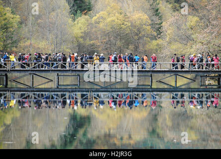 Die Reflexion der chinesischen Touristen, die auf der Brücke am fünf Blume Lake, Jiuzhaigou Nationalpark, China. Stockfoto