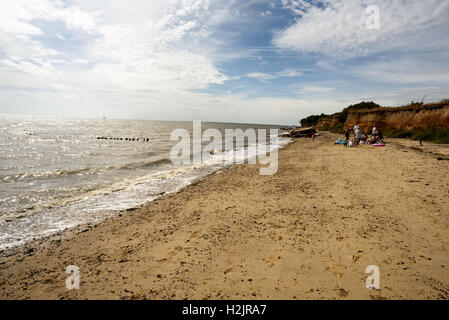 Gruppe von Mitgliedern der Öffentlichkeit entspannen Sie am Strand von Cudmore Grove in Mersea Essex England bei einem bewölkten Tag Stockfoto