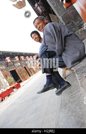 Zwei lokale chinesische Männer schießen die Brise in Pingyao, alte Stadt und UNESCO-Weltkulturerbe in der chinesischen Provinz Shanxi. Stockfoto