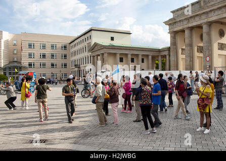 Asiatische Touristen versammeln sich vor dem Brandenburger Tor in Berlin. Einige von ihnen fotografieren. Stockfoto