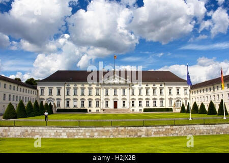 Blick auf Schloss Bellevue unter dramatische Wolken in Berlin. Eine Wache ist auch in der Szene. Stockfoto