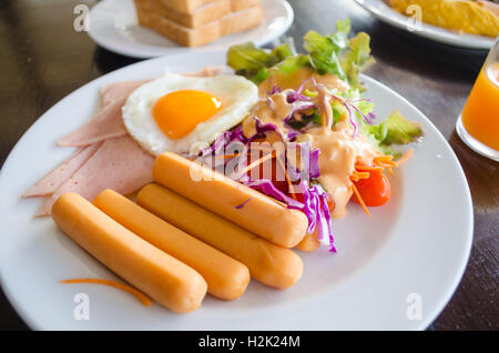 Frühstück mit Würstchen gebraten Ei und Salat Stockfoto