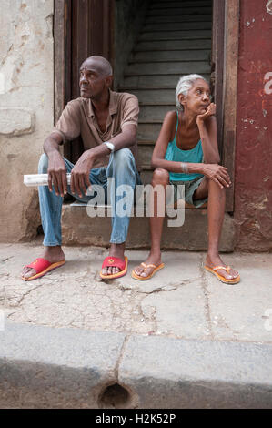 Havanna - 20. Mai 2011: Ein paar ältere Menschen sitzen Kubaner auf eine Tür Stoop in eine typische Straßenszene in Alt-Havanna. Stockfoto