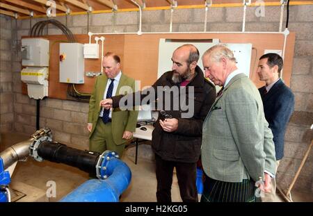 Der Prinz von Wales, auch bekannt als der Duke of Rothesay, mit leitender Projektingenieur Michael Bestwick und Estate Faktor Richard Glendson, als er das Braemar Wasserkraft Wasserkraftwerk Schema Turbinenhaus bei Linn Dee Road in Braemar öffnet. Stockfoto