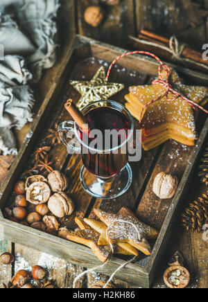 Glas Glühwein in Holztablett mit Weihnachten Dekoration Spielzeug, Lebkuchen, Nüssen, Zimt, Anis und Kiefer Kegel ov Stockfoto