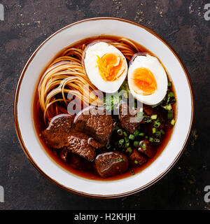 Asiatische Nudeln in Brühe mit langsamen Kochfleisch und Ei auf dunklem Hintergrund hautnah Stockfoto