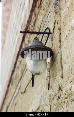 Alte Glaslaterne mit Lampenschirm an Ziegelwand Stockfoto