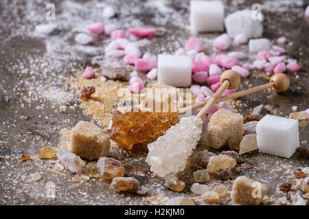 Vielzahl von Zucker weiß, braun, rosa Früchte granuliert, Würfel und Kristall über alte Textur Eisen Hintergrund. Nahaufnahme Stockfoto