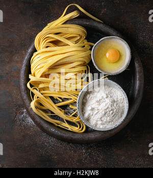 Rohe hausgemachte italienische Teigwaren Tagliatelle mit Nudeln Cutter, Schalen mit Weißmehl und gebrochene Ei in alten Ton Fach über d Stockfoto