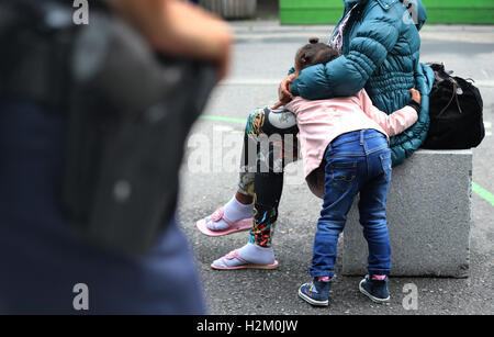 Konstanz, Deutschland. 19. Sep, 2016. Sithawit (25) aus Eritrea, die hochschwangere, Ahd ihre 4 jährige Tochter Winta, wartet hinter ein Polizist für einen Schiene Ersatz-Bus-Service, ihn zu Flüchtling Staatsempfang nehmen Zentrum in Karlsruhe, am Bahnhof in Konstanz, Deutschland, 19. September 2016. Foto: KARL-JOSEF HILDENBRAND/DPA/Alamy Live-Nachrichten Stockfoto