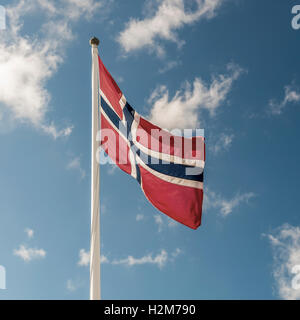 Eine norwegische Flagge flattert im Wind vor dem blauen Himmelshintergrund Stockfoto